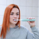 Woman brushing her teeth with electronic toothbrush in Colorado Springs